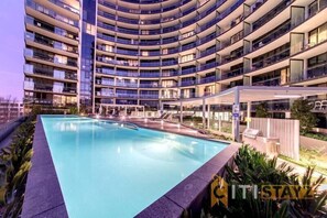 Un hôtel moderne doté d’une piscine circulaire, de nombreux balcons et d’un espace extérieur couvert.