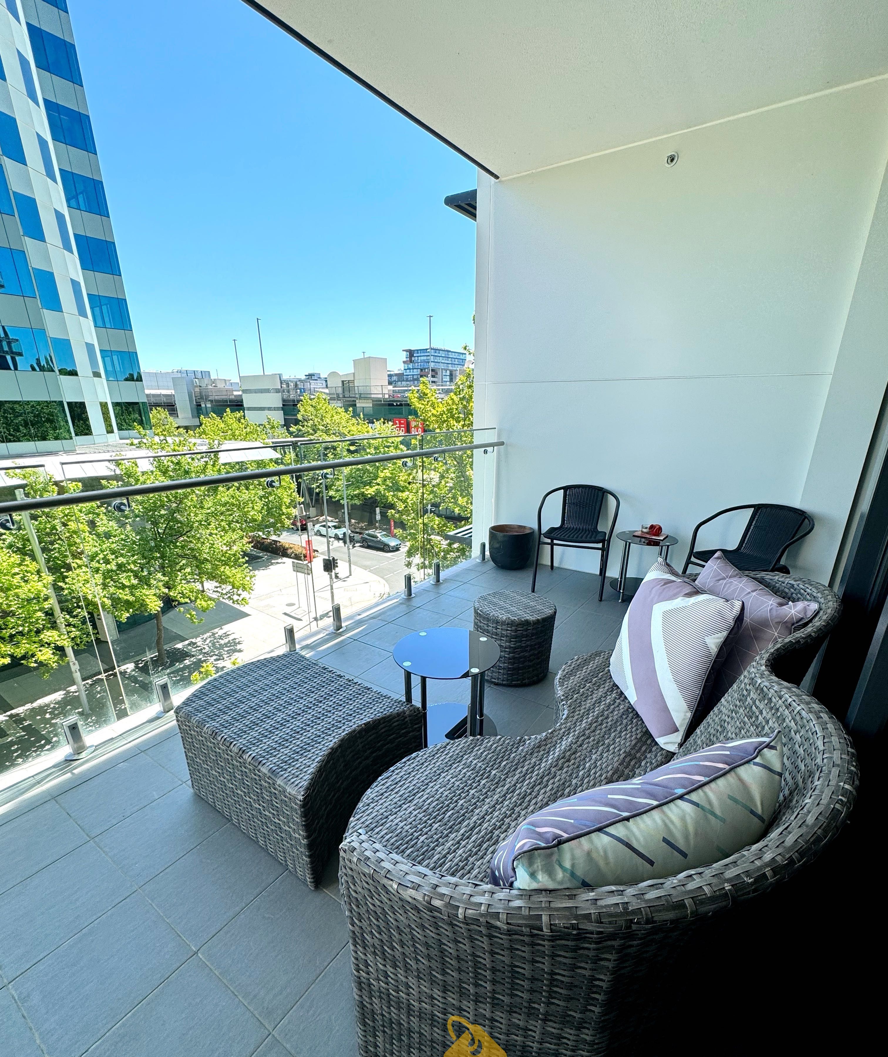 A balcony with wicker furniture, a small table, and a view of the cityscape.