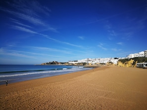 A wide sandy beach with a clear blue sky and calm sea.