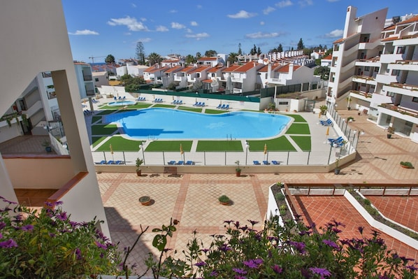 A pool area with blue water, surrounded by lounge chairs and potted plants.
