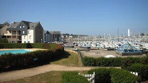 A marina with numerous boats, a swimming pool, and residential buildings in the foreground.