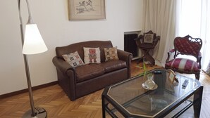 A living room with a brown leather sofa, a glass coffee table, a floor lamp, a framed picture on the wall, and a red upholstered chair. - Buenos Aires Recoleta, Super apartment 5 people! (Buenos Aires)