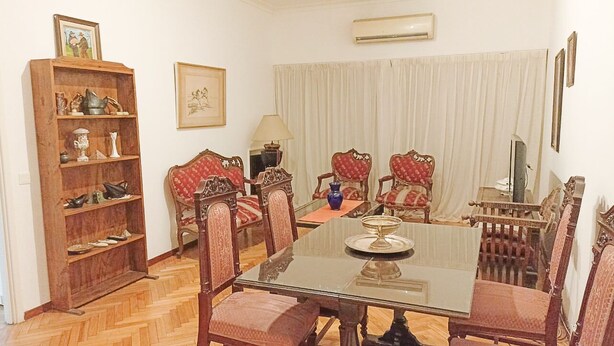 A dining room with a glass table, red upholstered chairs, a wooden sideboard, and a large window with curtains. - Buenos Aires Recoleta, Super apartment 5 people! (Buenos Aires)