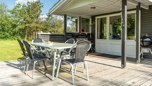 Una terrazza esterna con tavolo e sedie, un barbecue e una zona coperta con finestre.