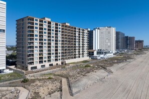 Un hotel de varios pisos con balcones, situado junto a una playa de arena.