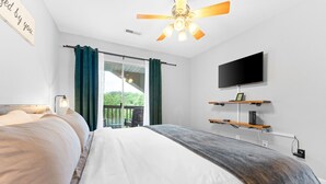A bedroom with a bed, a ceiling fan, a TV, and a window with curtains. - Next to Silver Dollar City - Lakeside Condo (Branson)