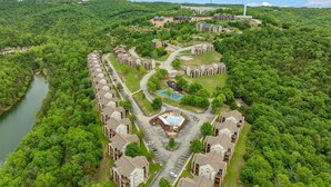 An aerial view of a residential area with multiple apartment buildings, a swimming pool, and a river. - Next to Silver Dollar City - Lakeside Condo (Branson)