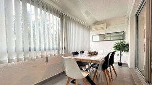 Een moderne eetruimte met een grote tafel, witte stoelen en een potplant.