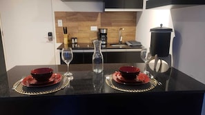 A modern kitchen with a black countertop, two red bowls on red plates, and two wine glasses.