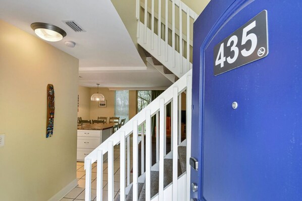 A blue door with the number 435, a white staircase, and a kitchen area in the background.