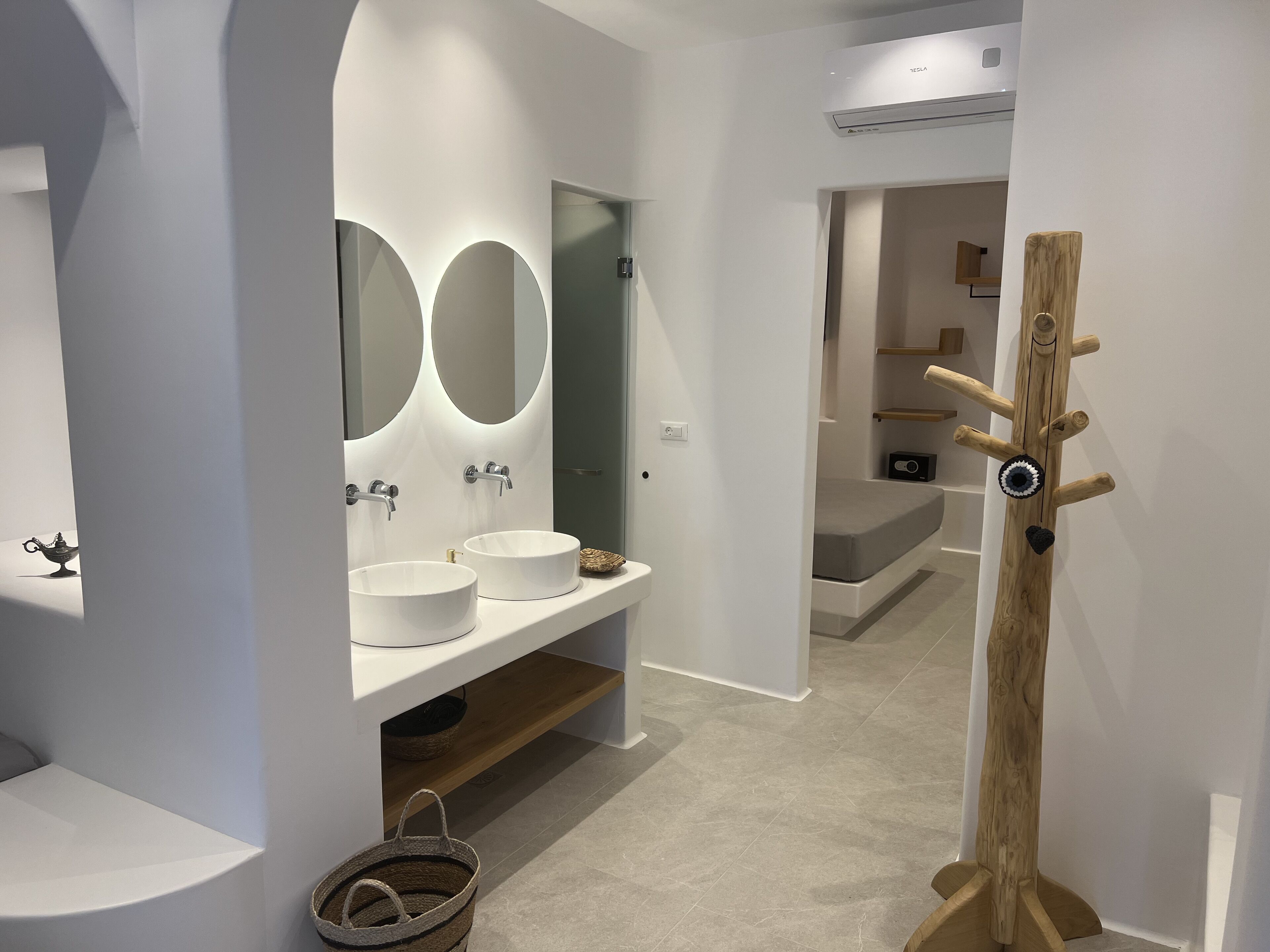 Un baño moderno con dos lavamanos, tocador y perchero de madera.