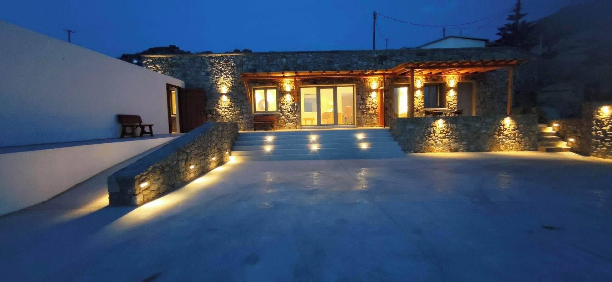 A stone house with a covered patio and a staircase leading to the entrance.
