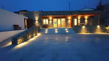 A stone house with a covered patio and a staircase leading to the entrance.