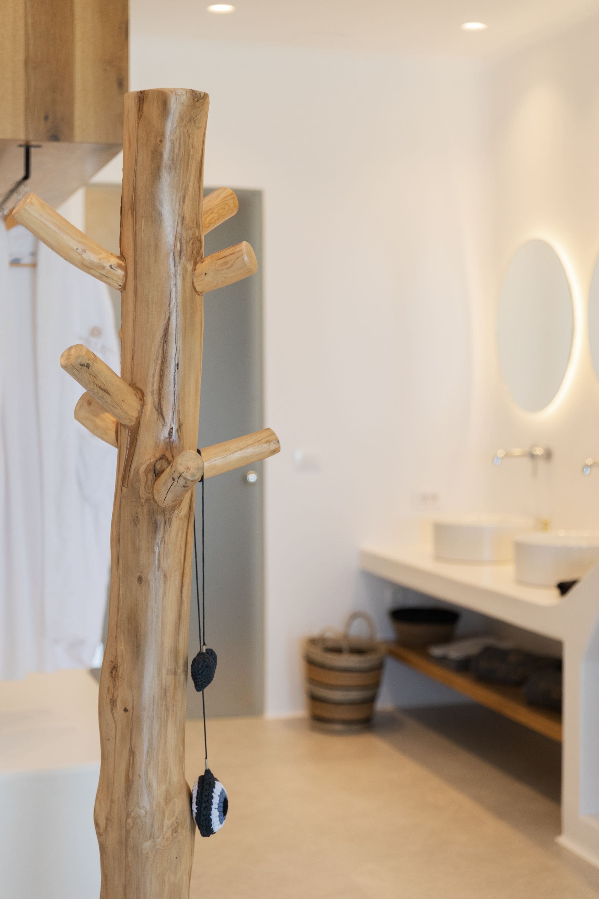 A bathroom with a wooden coat rack, a sink, and a mirror.