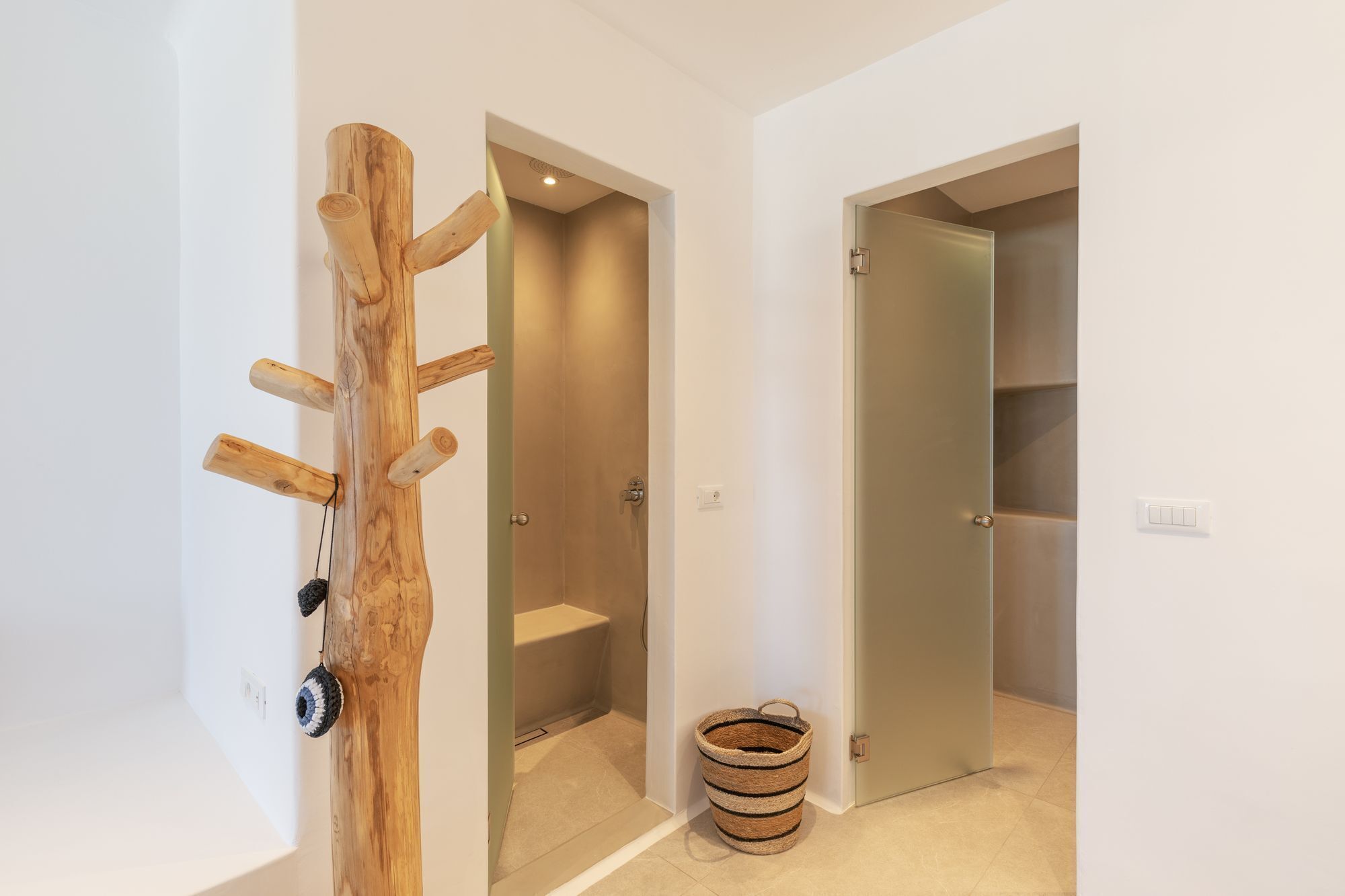 A hallway with a wooden coat rack, a basket, and two doors leading to rooms.