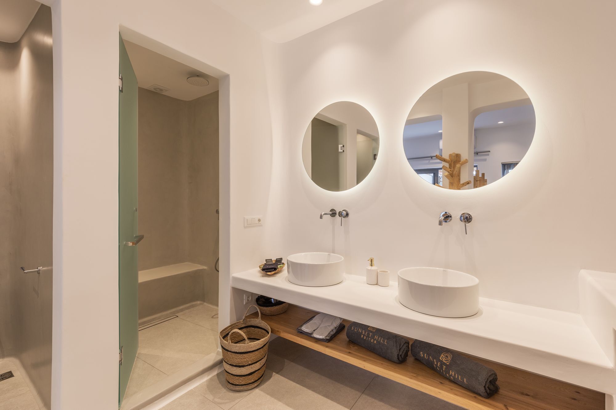 A modern bathroom with two round mirrors, a white sink, and a shower area.