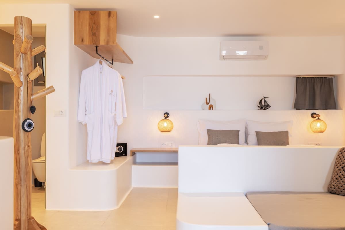 A modern, minimalist room with a curved seating area, a built-in bench, and a small table. There is a wooden structure on the left, possibly a storage or decorative piece.