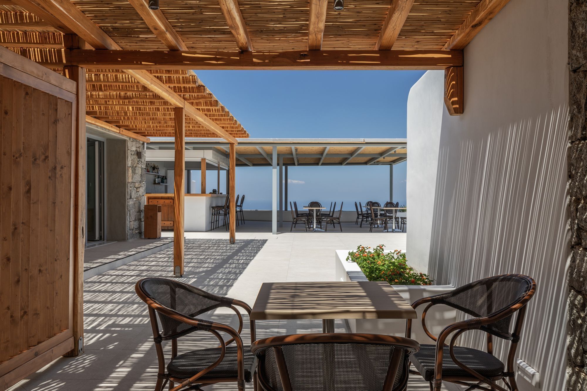 A covered outdoor seating area with wicker chairs and a table, overlooking a scenic view.