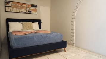 A bed with a dark headboard, white and beige pillows, and a blue blanket.