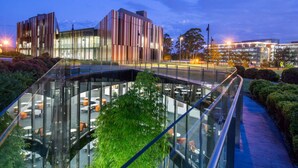 A modern building with a glass facade and a curved glass bridge leading to an outdoor seating area. - Neogaia Bed & Breakfast (West Pennant Hills)