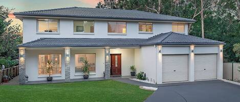 A two-story house with a garage, large windows, and a well-maintained lawn.