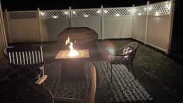 Un espacio patio al aire libre con una chimenea, asientos y una valla decorativa.