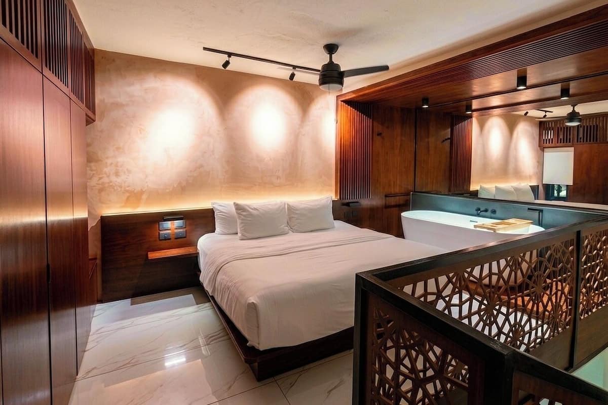 A modern bedroom with a large bed, a built-in vanity, and a ceiling fan.