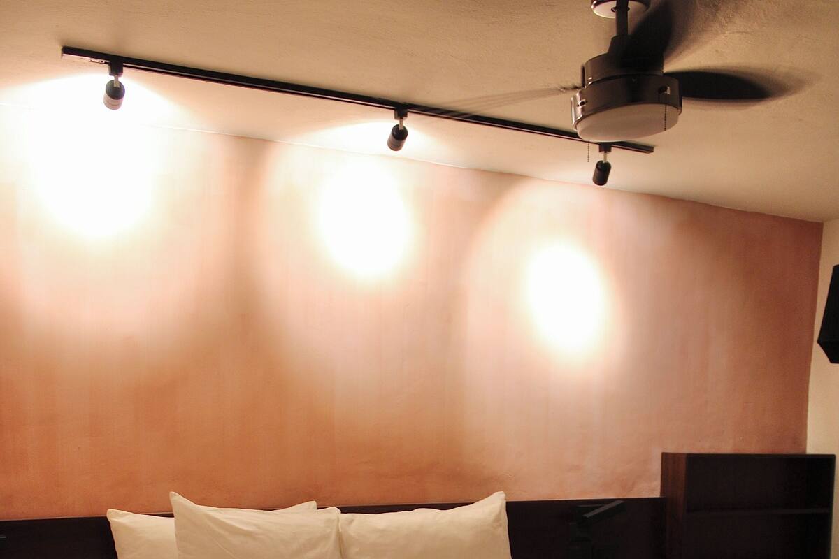 A neatly made bed with a wooden headboard, a bedside table, and a ceiling fan.