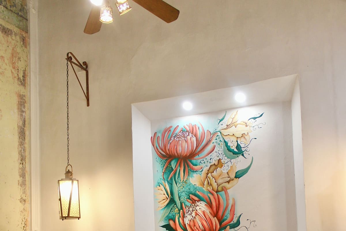 A bedroom with a large bed, a wall-mounted light fixture, and a ceiling fan.
