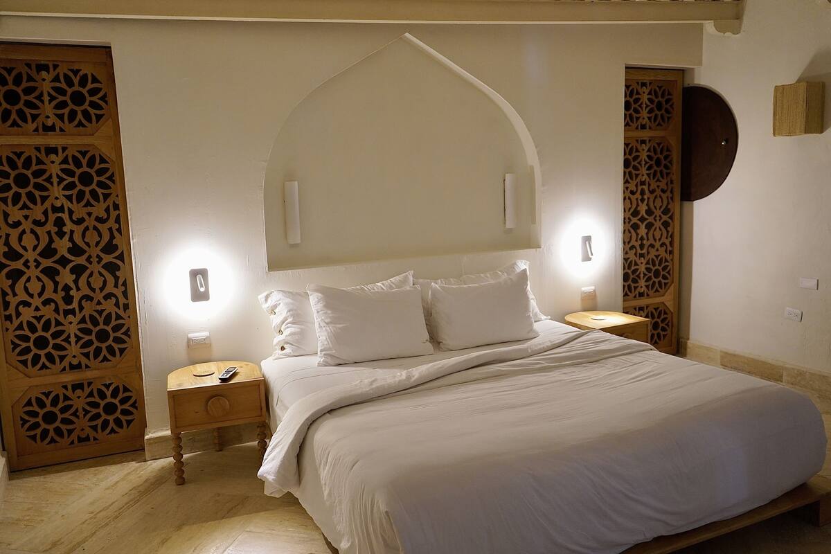 A bedroom with a large bed, two bedside tables, and decorative wooden panels.