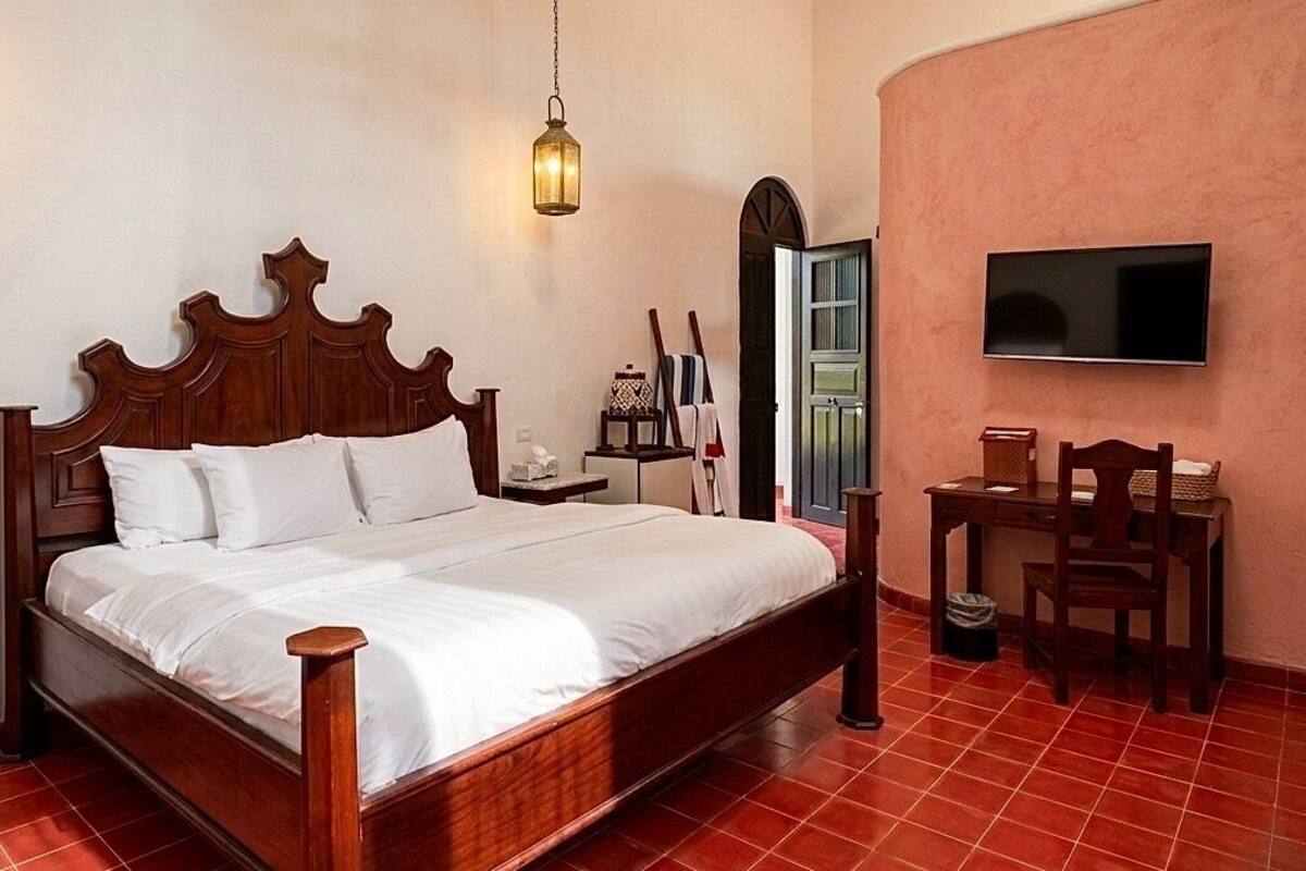 A bedroom with a wooden bed, a nightstand, a TV, and a chair.
