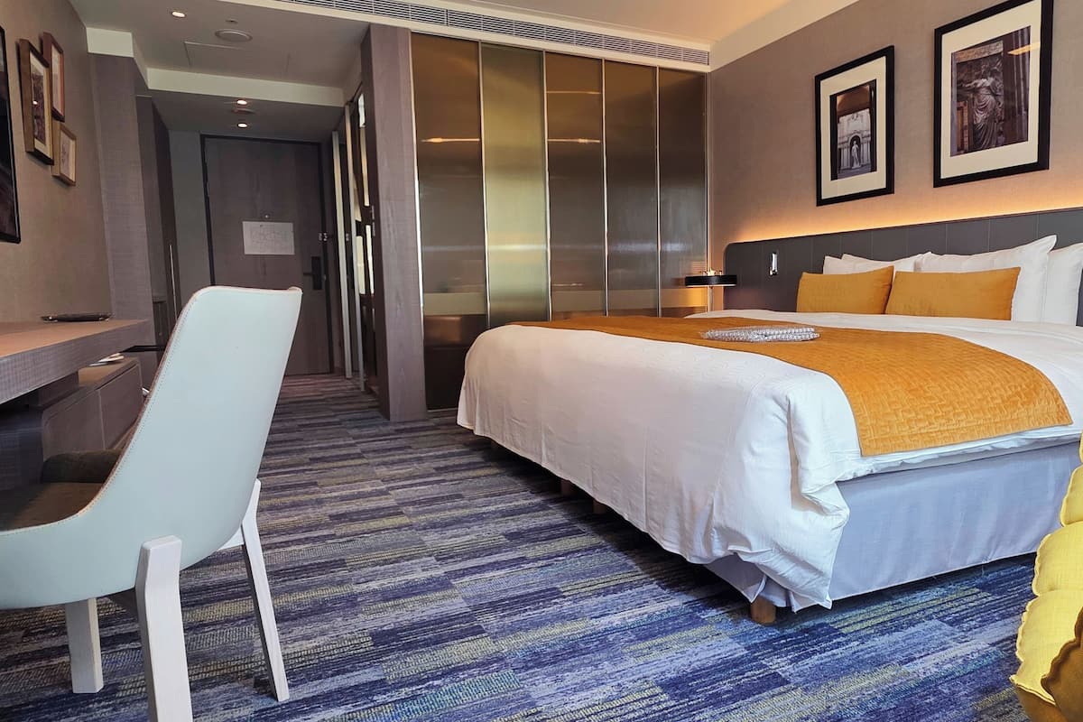 Een hotelkamer met een groot bed, een bureau en een stoel.