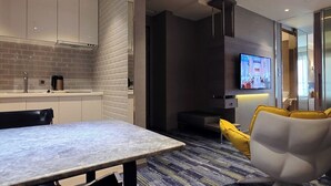 Une chambre d’hôtel moderne dotée d’un coin cuisine, d’une table à manger et d’un espace salon avec un téléviseur.