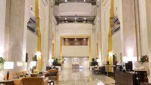 Un hall d’entrée spacieux avec un plafond haut, un mobilier moderne et un comptoir d’accueil central.