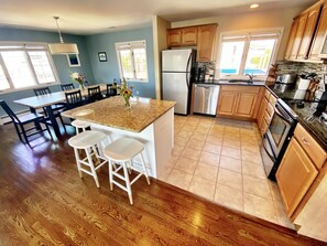 A kitchen with wooden cabinets, a granite countertop, a refrigerator, a dishwasher, and a stove.