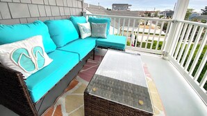 Un balcon avec un canapé turquoise, une petite table et un tapis à motifs.