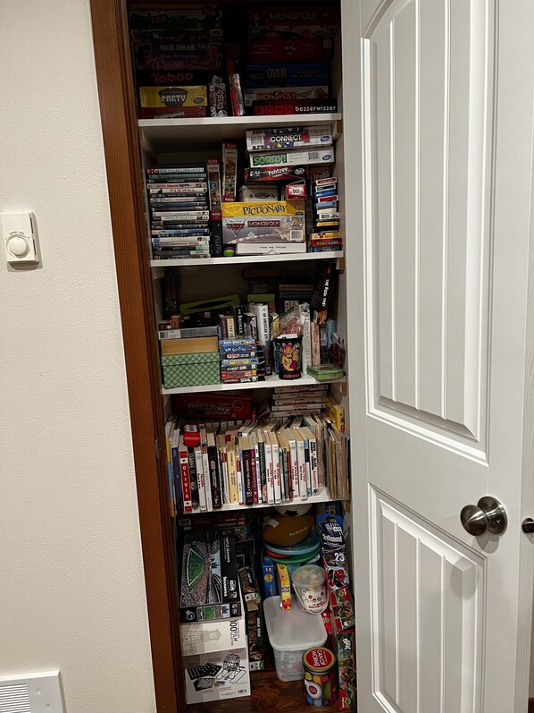 A narrow hallway with shelves stocked with board games and books.