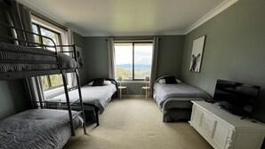 Une chambre avec des lits superposés, un bureau, une télévision et une fenêtre donnant sur un paysage agréable.