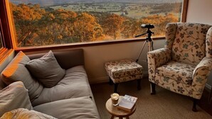 Une pièce confortable avec une grande fenêtre donnant sur un paysage magnifique, avec une vallée et des montagnes en toile de fond.