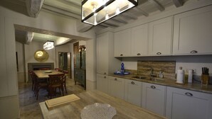Uma cozinha moderna com armários brancos, bancada de madeira e um espaço de refeições com mesa e cadeiras.