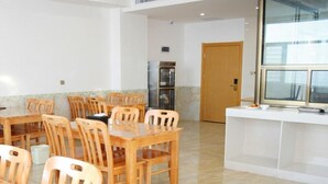 Comedor con mesas y sillas de madera, refrigerador y ventana con persianas.