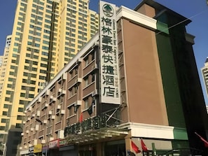 Um hotel com vários andares e uma placa chamativa na fachada.