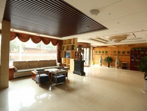 Eine geräumige Lobby mit einer Sofaecke, einer Statue und einem Empfangsbereich.