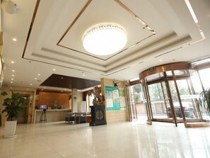 A hotel lobby with a reception desk, a large circular light fixture, a glass elevator, and a potted plant. - Greentree Inn Taiyuan East Binhe Road Xiaodian High Speed Mouth Express Hotel (Taiyuan)