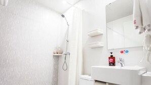 Un baño moderno con ducha, inodoro, lavamanos y espejo.