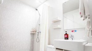 Un baño moderno con ducha, inodoro, lavabo y espejo.