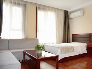 A hotel room with a bed, a sofa, a small table with a plant, and an air conditioning unit on the wall. - Greentree Inn Taiyuan East Binhe Road Xiaodian High Speed Mouth Express Hotel (Taiyuan)
