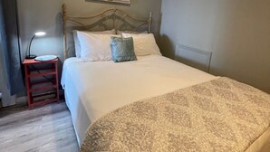 A neatly made bed with a patterned throw, a bedside lamp, and a small red nightstand. -    LAST MINUTE VACATION?  JULY 20-JULY 22.  LOW RATES. (Moneta)