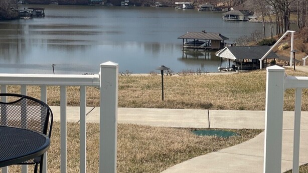 A lakeside view from a deck with a metal table and chairs, a concrete pathway, and a small dock with a gazebo. -    LAST MINUTE VACATION?  JULY 20-JULY 22.  LOW RATES. (Moneta)