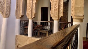 An interior courtyard with ornate arches and a wooden railing. - Riad Laksiba (Marrakech)